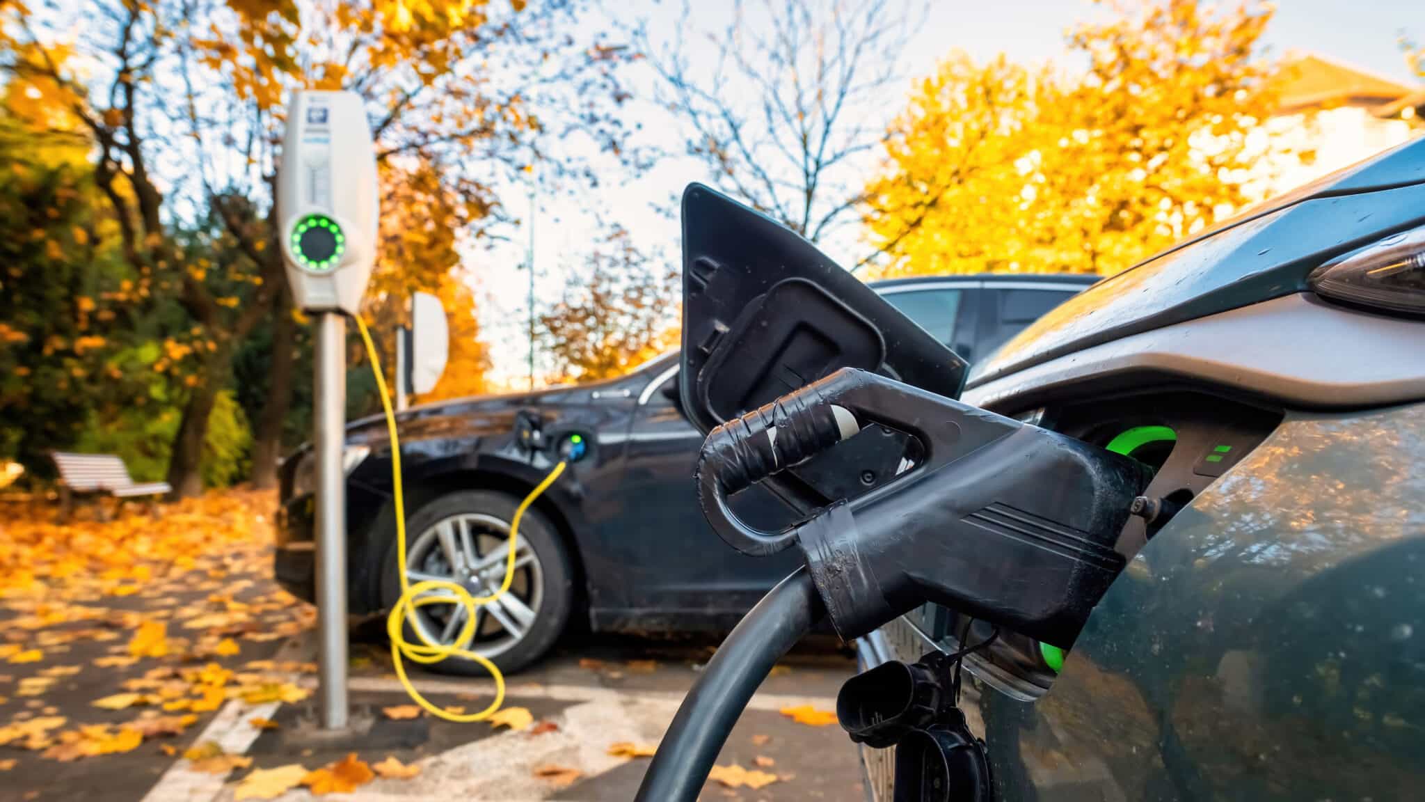 Two charging cars at a charging station on a street in a town, autumn